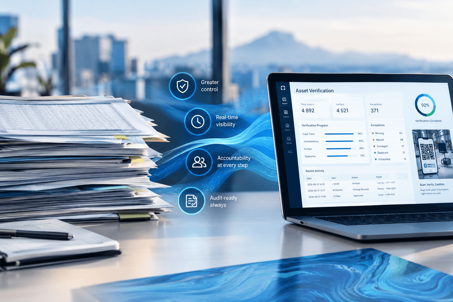 Pile of papers on a desk. A computer showing Fixed Asset Management.